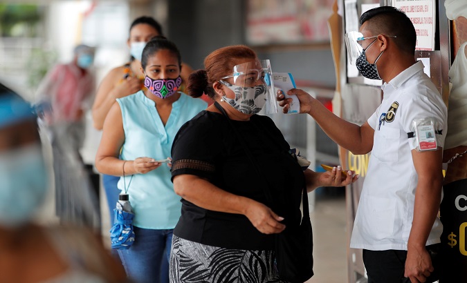An employee measures the temperature of a client at a supermarket, Panama City, Panama, Jan. 4, 2021.
