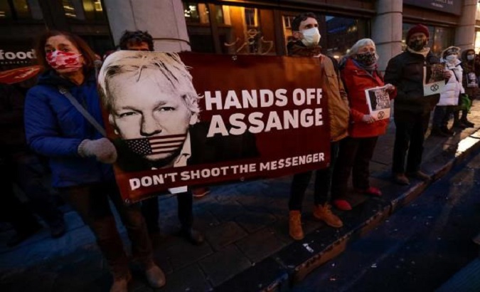 A demonstrator holds a placard with Julian Assange's photograph in front of the U.K. Embassy in Brussels, Belgium, January 4, 2021.