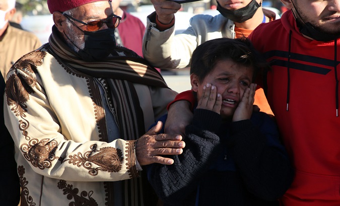 A child mourns a member of his family found in a mass grave, Tripoli, Libya, Jan. 22, 2021.