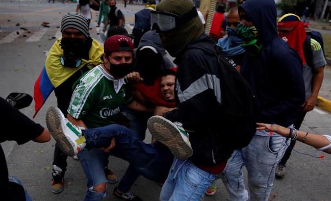 Demonstrators carry an injured person shot by an agent in Cali, Colombia, May 28, 2021.