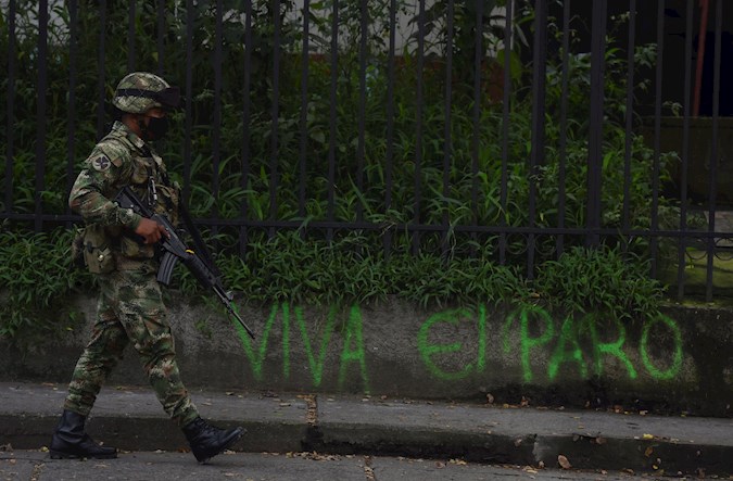 A Colombian soldier passes by a sign calling for strike support