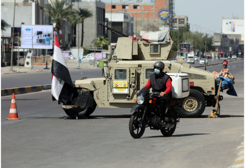 A delivery worker passes a mobile checkpoint  in Baghdad, Iraq
