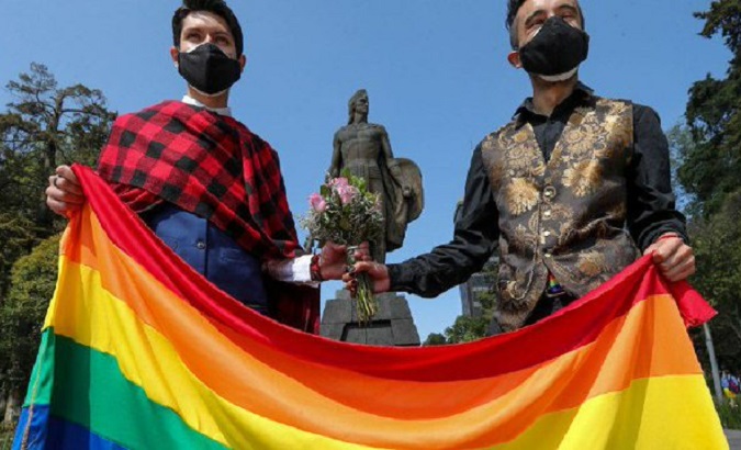 An LGTBI couple holds a multicolored flag, Mexico, 2021.