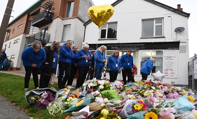 A group of people leaves flowers for Sir David Amess near the crime scene, Leigh-on-Sea, U.K, Oct. 16, 2021.
