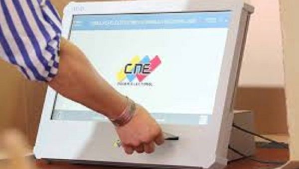 A woman introduces her ballot into an electoral machine, Venezuela, 2021. 