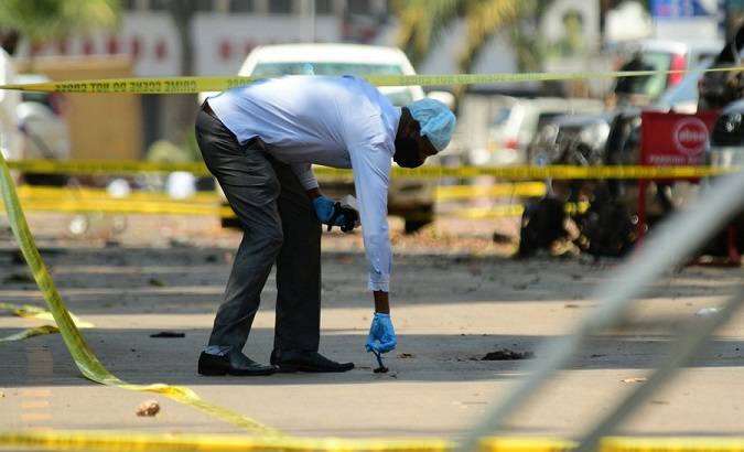 An investigator collects samples from the scene of a bomb blast, Kampala, Uganda, Nov. 17, 2021.