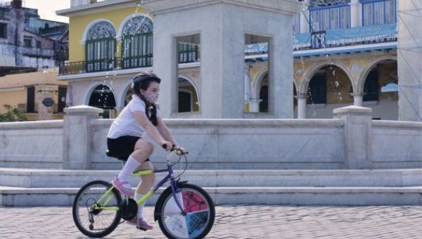 A girl wearing a mask rides bike amid the COVID-19 pandemic in Havana, Cuba, Nov. 26, 2020.
