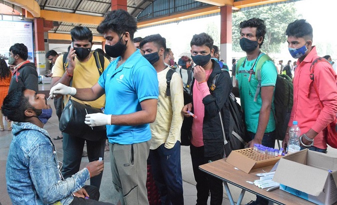 A health worker takes swab samples of travelers for COVID-19 nucleic testing outside a train station, Bangalore, India, Nov. 27, 2021.