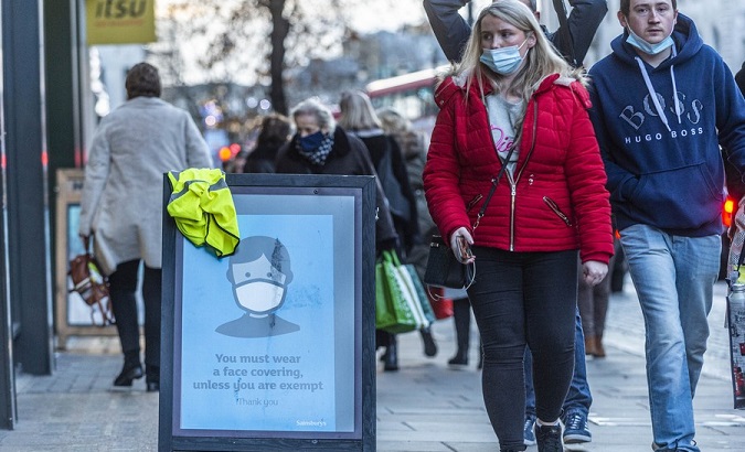 People walk past a sign requiring people to wear face coverings in London, Britain, on Dec. 9, 2021.