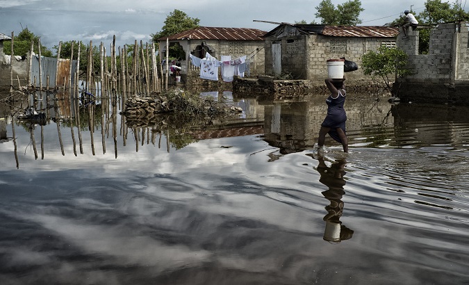 A woman walks down a flooded street, Haiti, 2022.