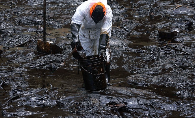 Worker cleans up pollution caused by the oil spill in Peru, Jan. 28, 2022.