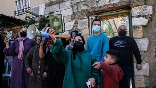 A Palestinian woman holds the Quran as Israeli settlers assault a family, Sheikh Jarrah neighborhood, Feb. 13, 2022.