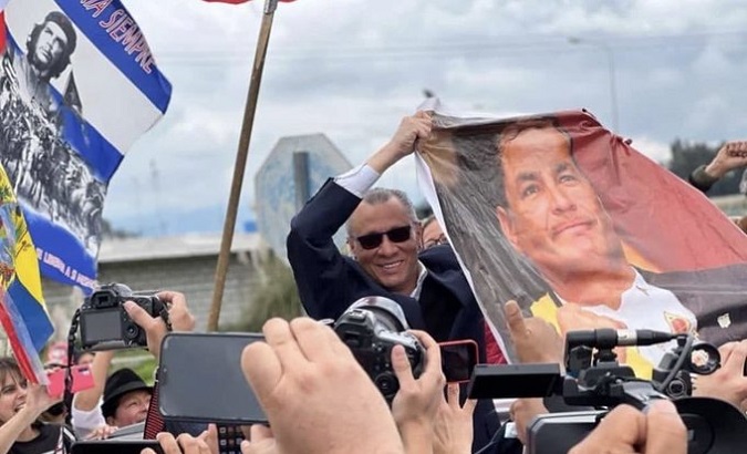 Jorge Glas holds an image of ex-President Rafael Correa, April 10, 2022.