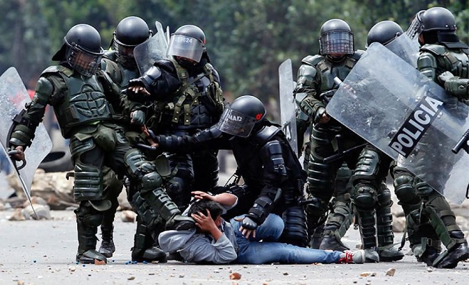 Police officers beat a protester, Colombia.