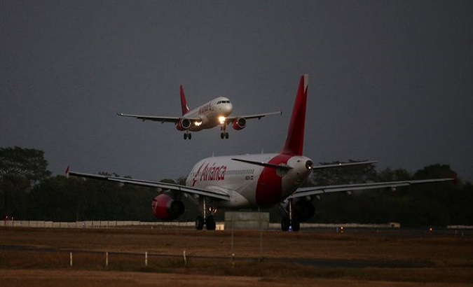 An Avianca Airlines plane lands while another prepares to take off at San Oscar Arnulfo Romero International Airport, San Luis Talpa, El Salvador, Feb. 8, 2022.