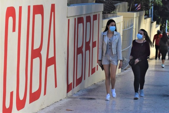 People wearing face masks walk on a street in Havana, Cuba, Jan. 17, 2022.