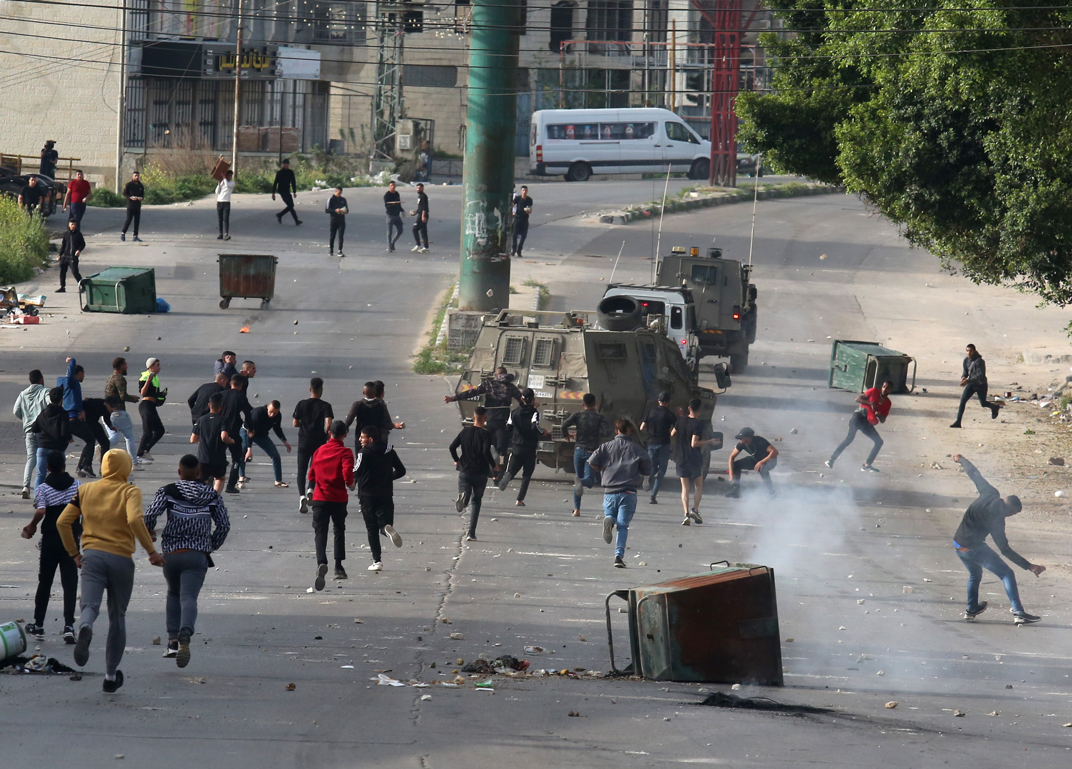Protesters hurl stones at an Israeli military vehicle during clashes following a raid in the West Bank city of Nablus, April 11, 2022