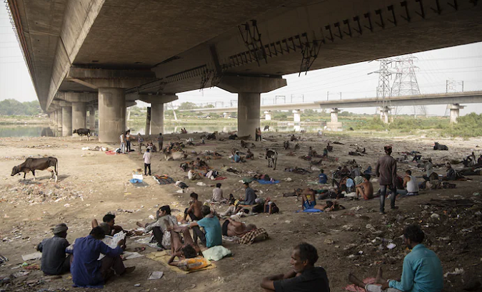 People take shelter from the intense heat under a bridge, New Delhi, May 29, 2022.