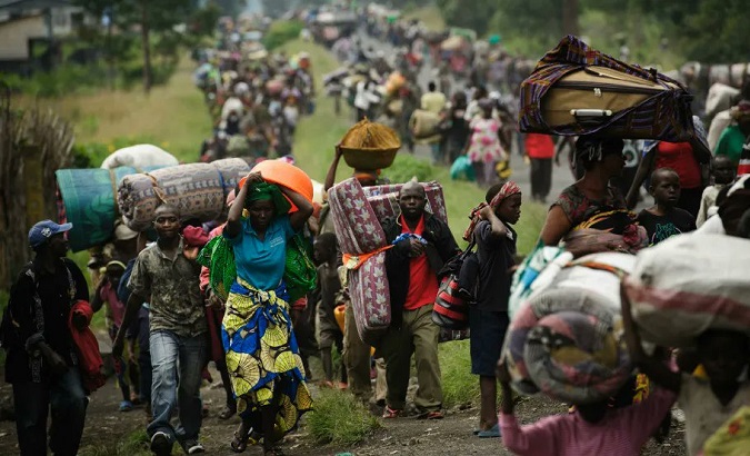 Refugees walk carrying a few belongings, Uganda, 2022.