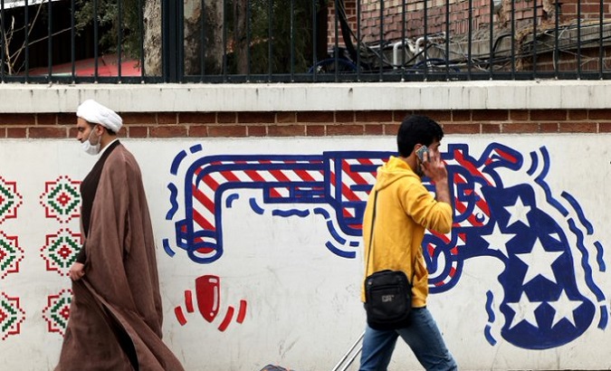 Iranians walk past graffiti against the U.S. sanctions.