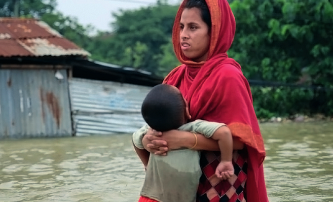 A woman holds her child amid flooding, Bangladesh, June 28, 2022.