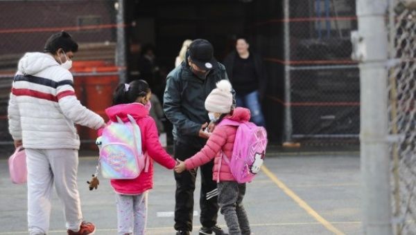 Children greet each other as they arrive at school in New York, the United States, March 7, 2022.
