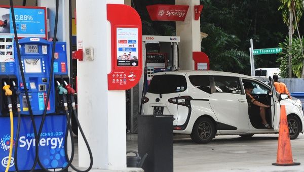 People fuel their vehicles at a petrol station in Singapore on May 13, 2022.