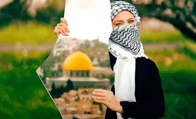 A Palestinean woman holds a mirror.