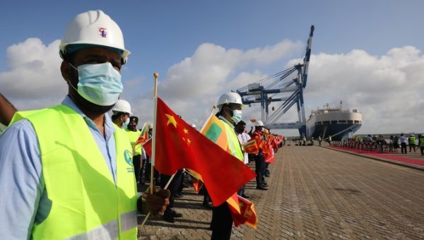 Port workers wave Sri Lankan and Chinese national flags during a welcoming ceremony of Chinese research and survey vessel 'Yuan Wang 5'