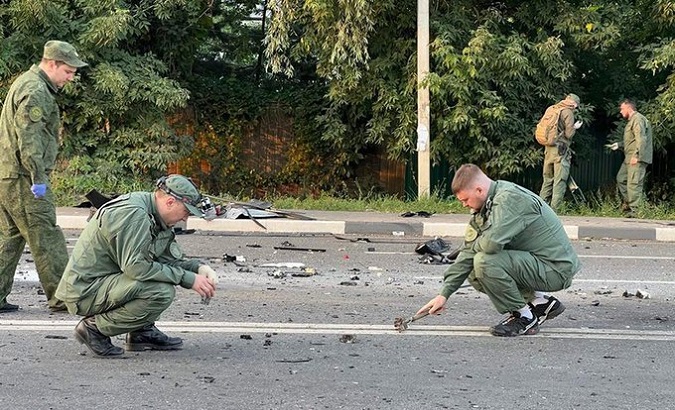 Russian military inspect the area where the car exploded, Aug. 22, 2022.