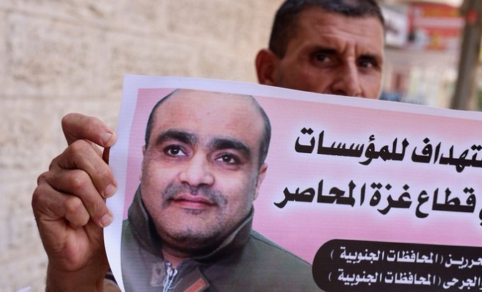 A man holding a photo of Mohammad El Halabi.