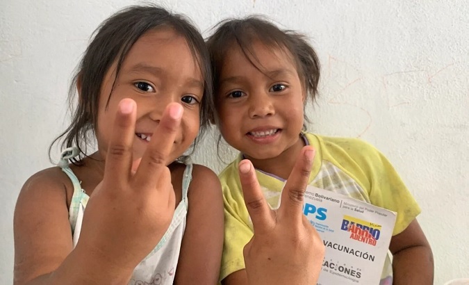 Venezuelan girls display their vaccination card, 2022.