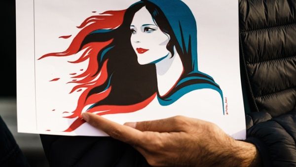 A participant holds an illustration showing Mahsa Amini during a rally in Berlin, Germany, 23 September 2022.