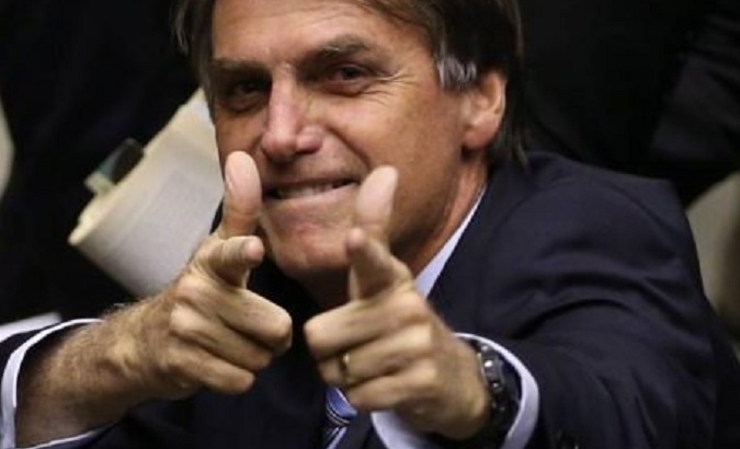 Jair Bolsonaro simulating with his hands that he fires weapons.