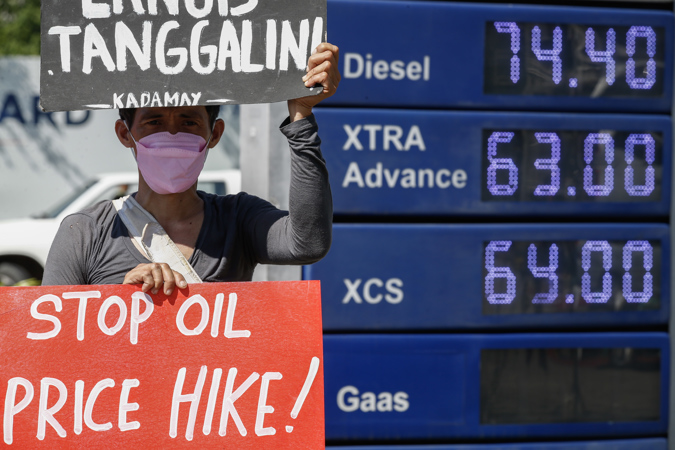 A protester holds a sign during a rally against fuel price hikes at a fuel refilling station in Quezon City, Metro Manila, Philippines 11 October 2022.