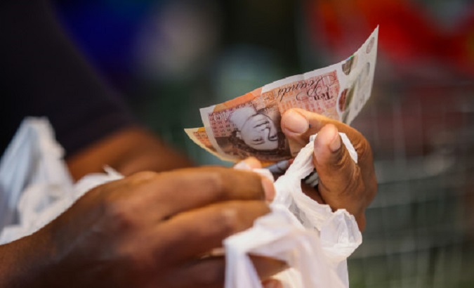 A person holding pound sterling notes.