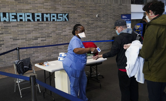 A medical worker checks temperatures for visitors at a hospital in New York, U.S., Dec. 13, 2021
