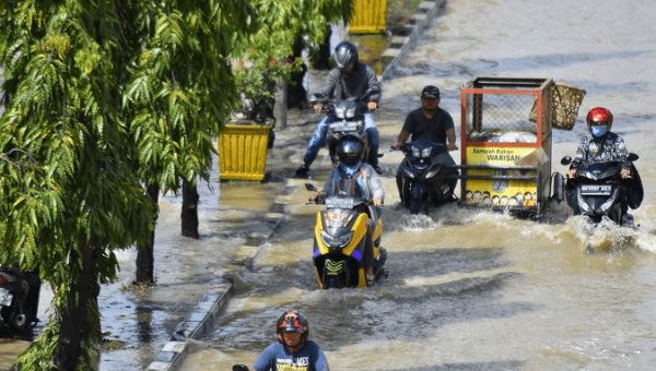 People ride motorbikes through flood water in Medan, Indonesia, Nov. 19, 2022.