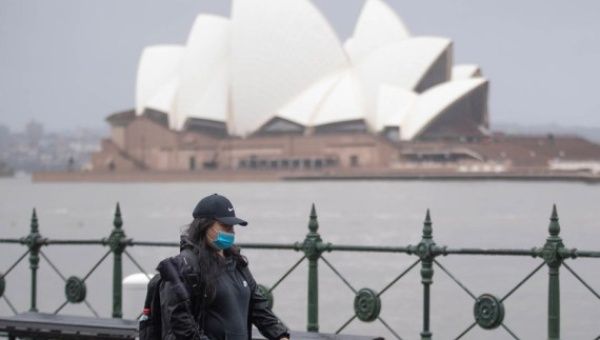 A woman walks past Sydney Opera House in Sydney, Australia, on July, 6, 2022.