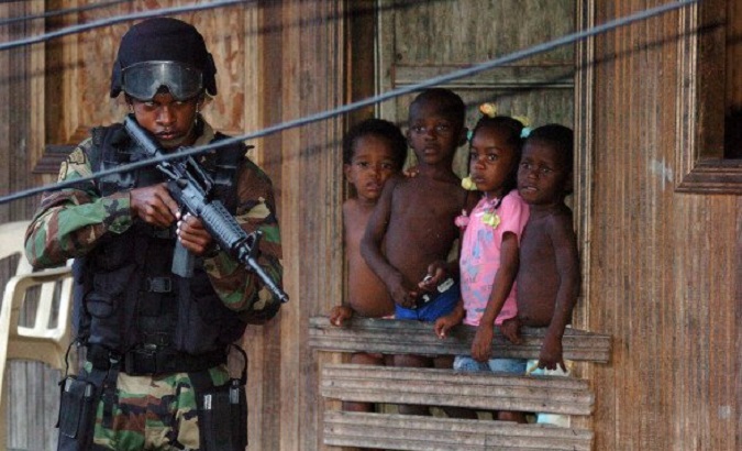 Colombian children watch an armed man.