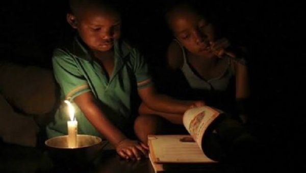 Children read by candlelight, South Africa, 2022.