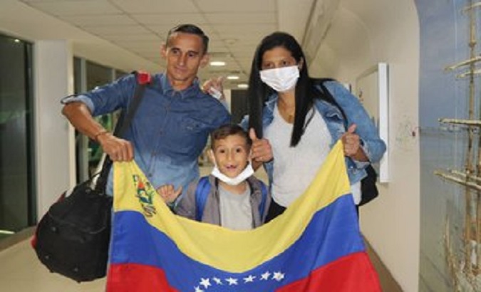A family of migrants show their national flag, Maiquetia, Venezuela, Jan. 10, 2023.