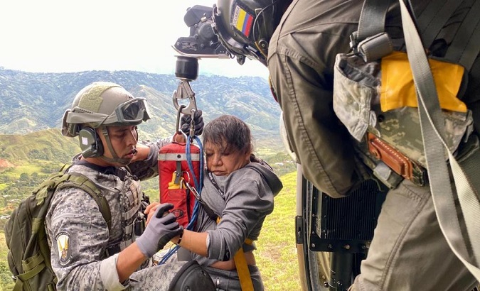 Military men assist a woman affected by landslides, Cali, Colombia, Jan. 10, 2023.