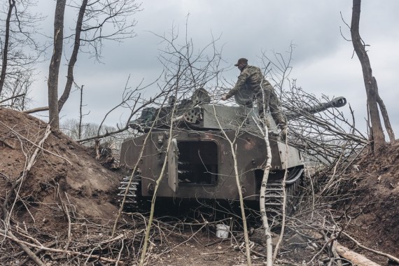 A Ukrainian soldier covers an armored vehicle with branches in Donbass on April 12, 2022.