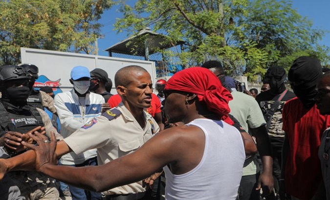 A police officer prevents a citizen from entering a street, Haiti.