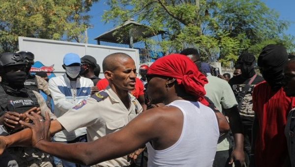 A police officer prevents a citizen from entering a street, Haiti. 
