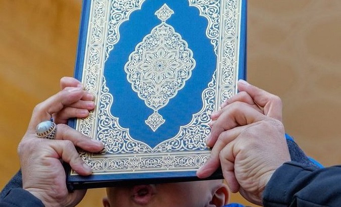A person holds a copy of the Quran.
