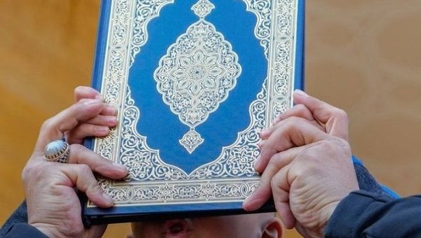 A person holds a copy of the Quran.