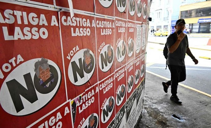 Ecuadorian citizen walks near posters against the referendum proposed by President Guillermo Lasso.