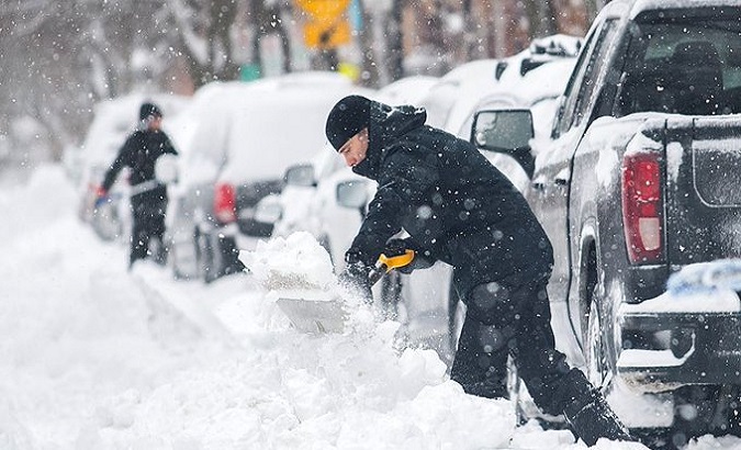 A man shovels snow off a road, Canada.